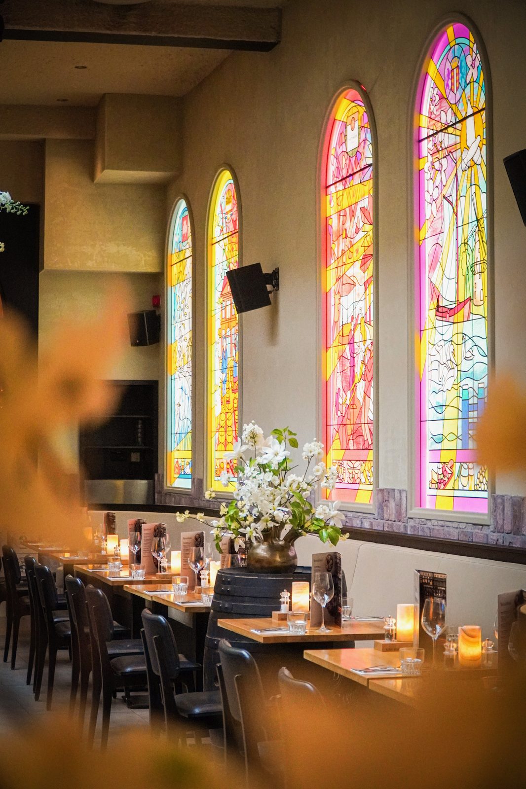 Glas-in-lood ramen met gedekte tafels en kaarslicht bij Gouds Glas